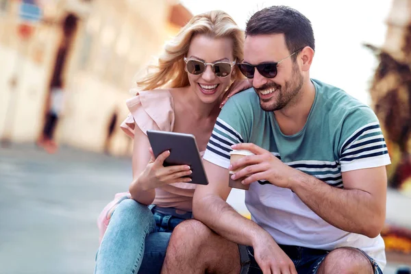 微笑的年轻夫妇看现代平板电脑 而坐在市中心 — 图库照片
