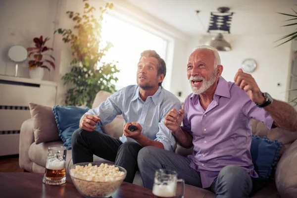Ojciec Syn Oglądanie Telewizji Pije Piwo Jedzenie Popcorn Domu — Zdjęcie stockowe