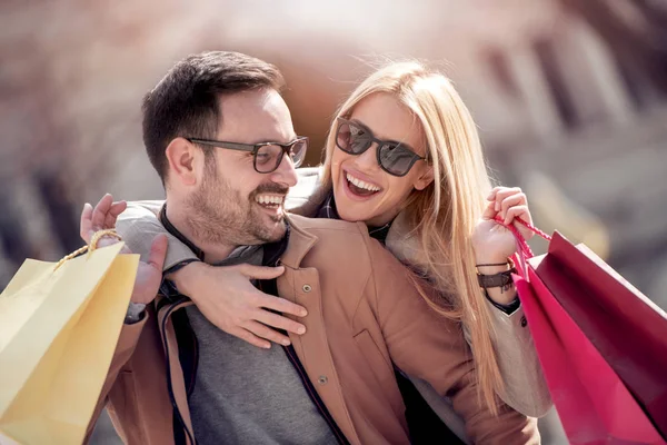 young couple with shopping bags walking down street