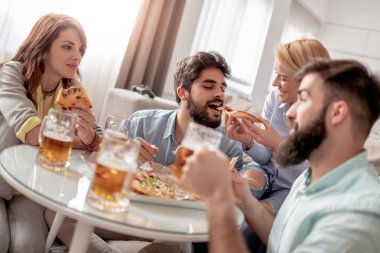 Pizza yeme ve evde bira içme arkadaşları gülümseyerek. Boş zaman, insanlar, yiyecek ve mutluluk kavramı.