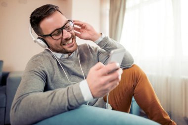Genç adam akıllı telefonunu evde müzik dinleme.