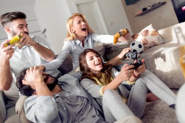 Modern apartmanda oturuyor ve video oyunları oynarken genç arkadaş grubu. Dostluk, teknoloji, Oyunlar ve ev kavramı.