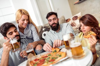 Pizza yeme ve soğuk bira içme sırasında evde TV izlerken arkadaşlar.