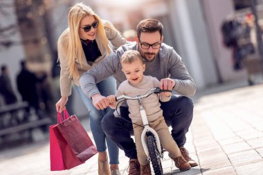 Baba ve oğulları eğleniyor Şehirde güneşli günde Bisiklet ang binmek için öğretim anne.
