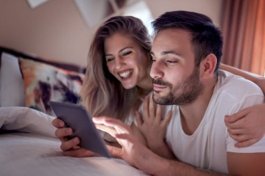 Genç çift Tablet yatağa gece kullanma.