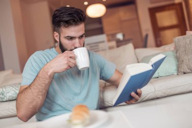 Yakışıklı olan kitap ve holding kahve Kupası okuma sabah portresi.