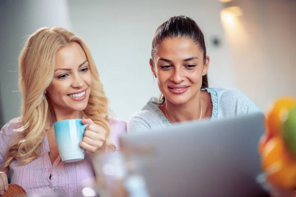 Two cheerful women with laptop,having fun together.