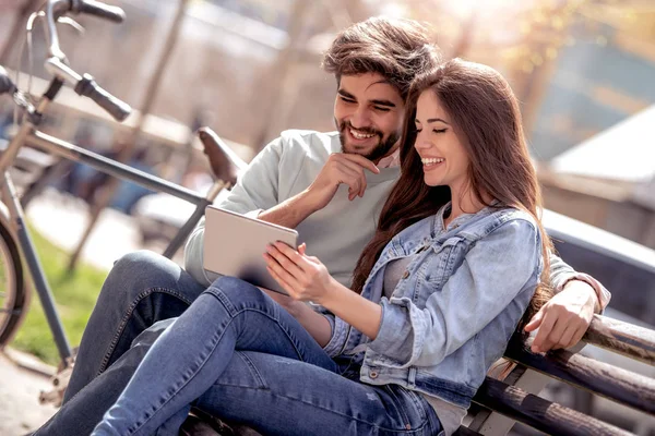 Junges Paar Sitzt Auf Parkbank Und Hat Spaß Mit Tablet — Stockfoto