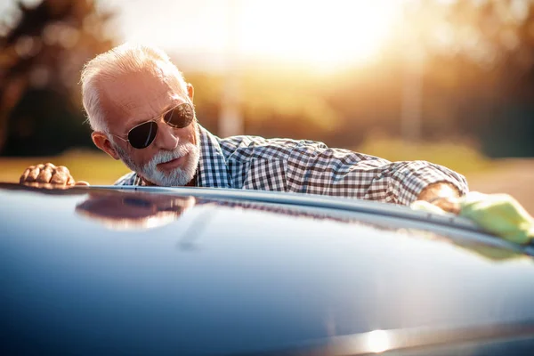 Senior man cleaning car on open air