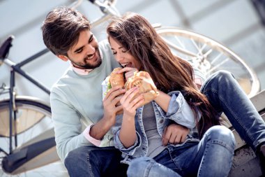 Merdivenlerde oturan ve sandviç açık havada yemek güzel sevgi dolu çift.