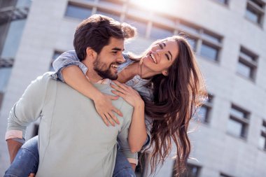 Güzel gülümseyen genç adam ve eğlenceli, sarılma ve zevk birbirimizi açık havada olan sevimli kadın portresi. 