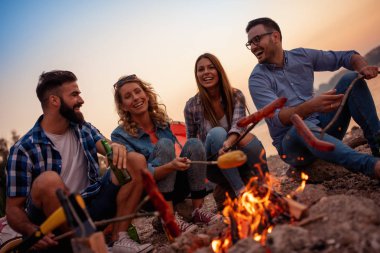 Geceleri ateşin yanında oturup, sosis ızgara ve büyük zaman sahilde olan arkadaş grubu.