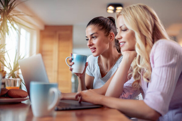 Two happy women looking at laptop, having great time
.