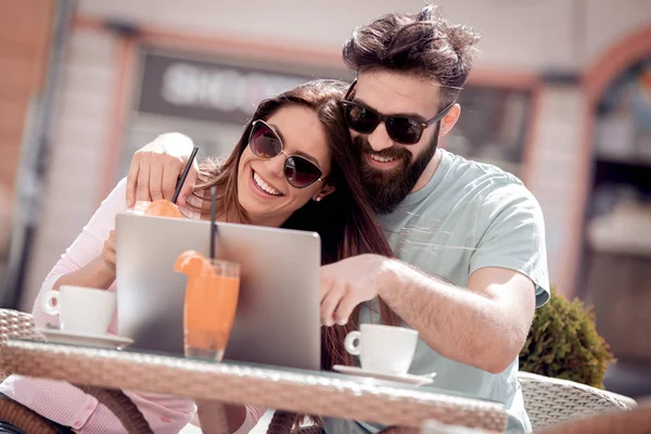 年轻夫妇在咖啡馆喝咖啡 他们面带微笑 看着笔记本电脑 — 图库照片