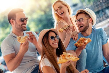 Açık havada eğleniyor, pizza yemek arkadaşlar.