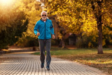 Kıdemli koşucu sonbahar parkında koşuyor.