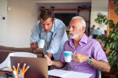 Modern ofiste dizüstü bilgisayarda çalışan iki işadamı..