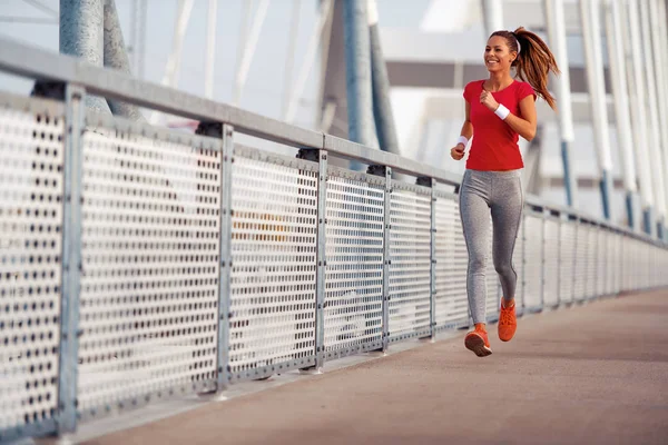 Running woman.Young fitness woman running on city bridge.