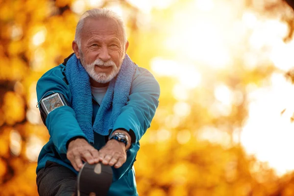 Active senior runner jogging in autumn park.