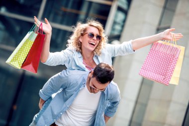 Şehirde alışveriş torbalarıyla genç ve mutlu bir çift, birlikte eğleniyorlar..