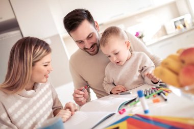 Anne ve baba evde çocuklarıyla birlikte resim çiziyorlar..