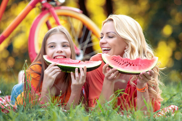 Family time.Mother and daughter eating watermelon in the park.