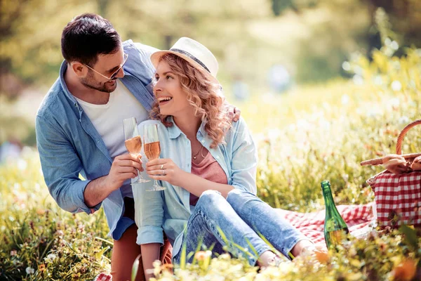 Love, dating, people and celebration concept - smiling couple drinking champagne at picnic.