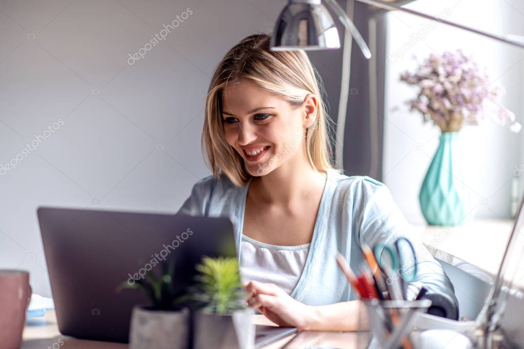Young beautiful woman working from a home with laptop.