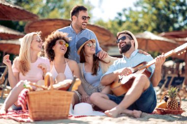 Mutlu arkadaş rahatlatıcı ve sahilde gitar çalmak. Beach partide eğleniyor.