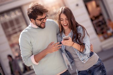 Mutlu genç çift açık havada birlikte ayakta ve hareket eden telefon arayan.