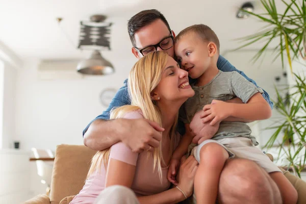 Young parents having fun with their son on bed at home.Family, parenthood,love and people concept