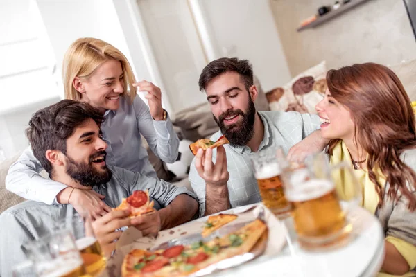 Pizza yeme ve soğuk bira içme sırasında evde TV izlerken arkadaşlar.