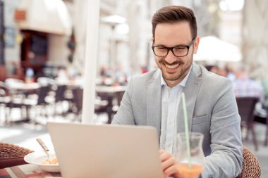 Restoranda oturan ve onun dizüstü bilgisayarda çalışan yakışıklı işadamı.