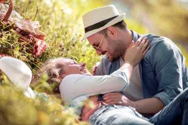 Mutlu çift gülüyor ve çim üzerinde yalan konuşuyor.