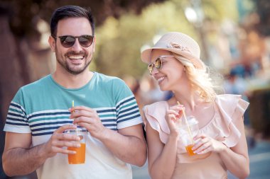 Genç çift ferahlatıcı parkta portakal suyu ile.