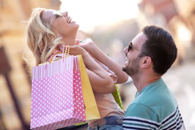 Alışveriş yaptıktan sonra alışveriş torbalarıyla mutlu bir çiftin portresi..