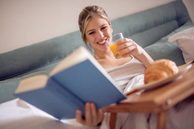 Yatakta kahvaltı ve bir kitap okuma güzel kadın.