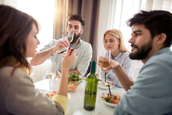 Leisure, eating, food and drinks, people and holidays concept - smiling friends having lunch and drinking wine at home.