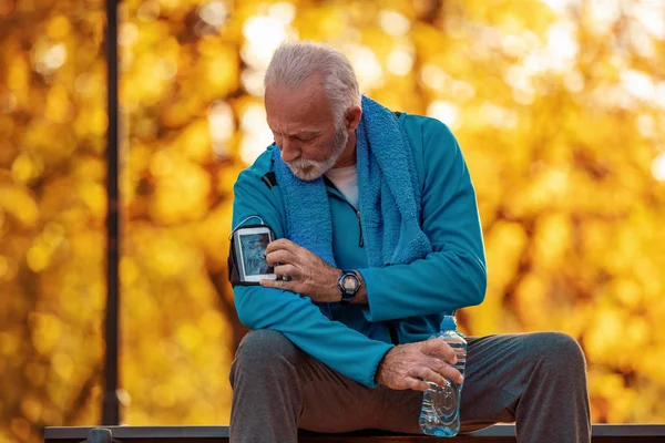 Senior runner doing stretching in autumn park.