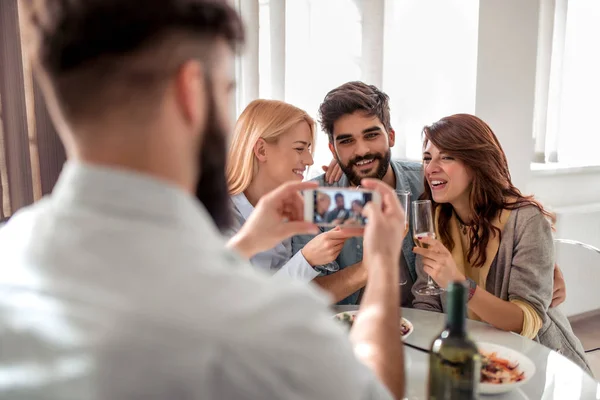 Leisure,friendship, people and holidays concept - happy friends having lunch and taking photo with smart phone.