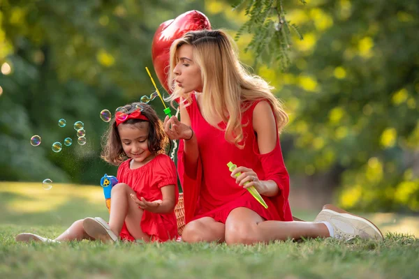 母と娘一緒に公園でシャボン玉を吹いて 楽しんで — ストック写真