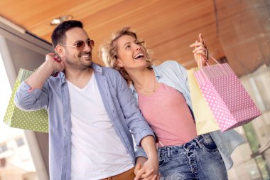 Satılık, tüketim ve insanlar kavramı - alışveriş torbaları vitrin City bakarak ile mutlu çift.