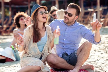 Mutlu genç çift plajda pikniğin tadını çıkarıyor ve yaz tatillerinde iyi vakit geçiriyor..