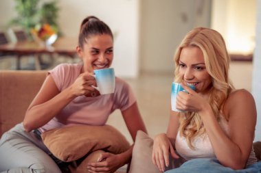 Genç kızlar kahve ile kanepede rahatlatıcı.