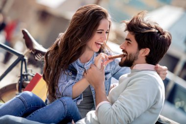 Mutlu genç çift açık havada eğleniyor, onlar yemek pasta ve gülümseyen.