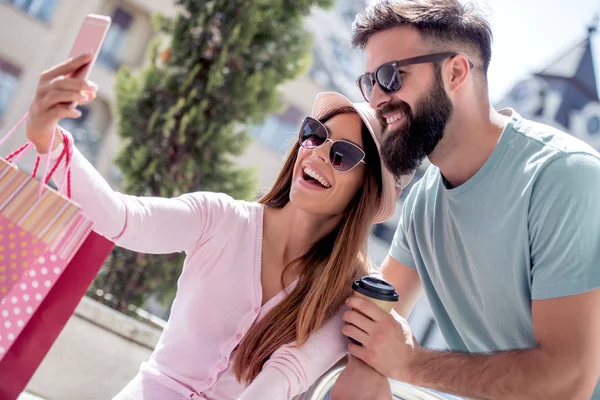 市内で買い物袋を持つスマート フォンと幸せなカップル撮影 Selfie — ストック写真