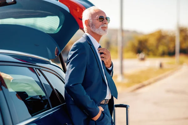 Senior businessman traveling to work wit car,having little break.