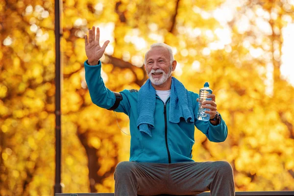 Senior runner doing stretching in autumn park.