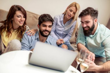 Birlikte kanepede oturan ve dizüstü film izlerken arkadaşlar.