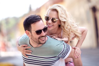 Dışarıda birbirine aşık gülümseyen bir çift. Sokakta sarılan mutlu genç bir çift..